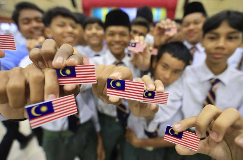 Abu Bakar yang bertugas sebagai juruteknik memakaikan lencana Jalur Gemilang pada pakaian seragam anaknya, Mohd Fakhrullah.