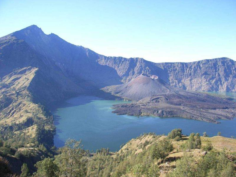 Gorgeous views reward trekkers who make the tedius hike to Rinjani National Park. Mount Rinjani (the left peak on the mountain range) is the third highest volcanic peak in Indonesia. Following countless eruptions, a new cone emerged from the lake (middle of the picture). This new and active peak called Gunung Barujari (2,363m) last erupted in October 2004.COPYRIGHT. PIX TO GO WITH SPECIFIC STORY. DO NOT REUSE. *** Local Caption *** Scenic vistas of the crater lake and peaks can distract a hiker as he makes his way down the crater of Mt Rinjani.