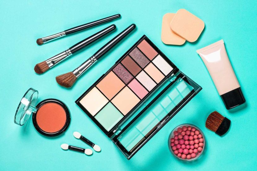 Makeup professional cosmetics on color mint background. Eyeshadows, concealer, face powder and brushes. Flat lay image.