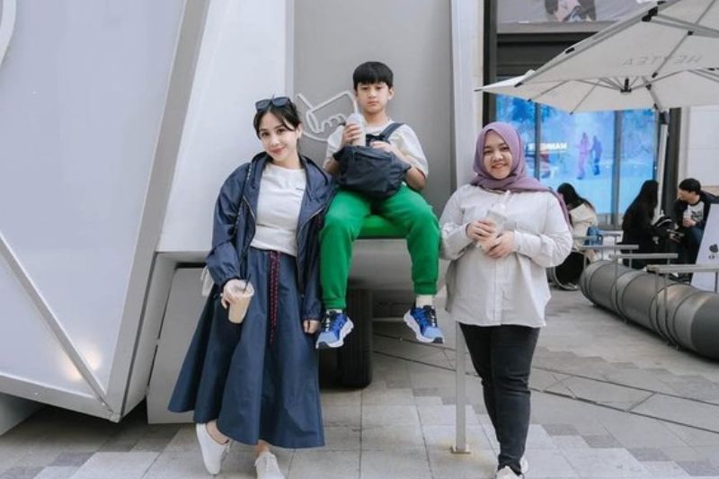 Nagita (kiri) bersama anaknya Rafathar (tengah) dan pengasuh (kanan) mereka.