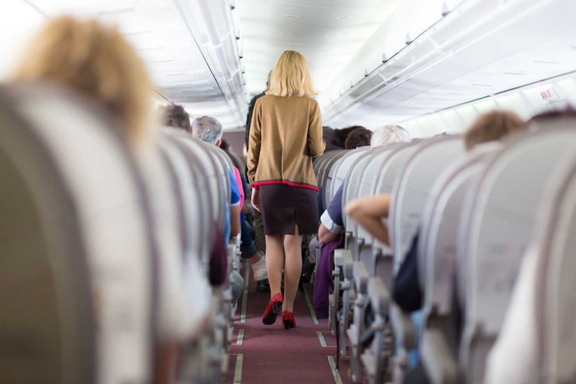 32506875 - interior of airplane with passengers on seats and stewardess walking the aisle.