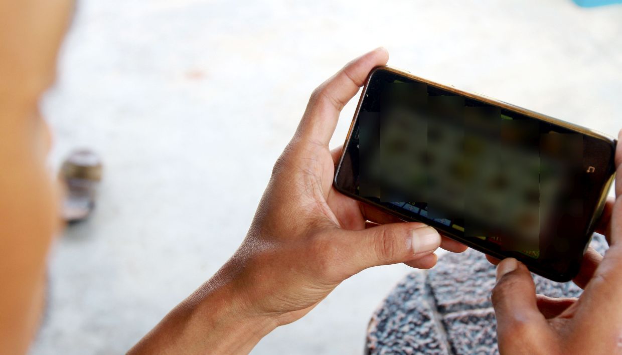 youth showing the online gambling using their mobile phone at Coffie shop in Melaka.
