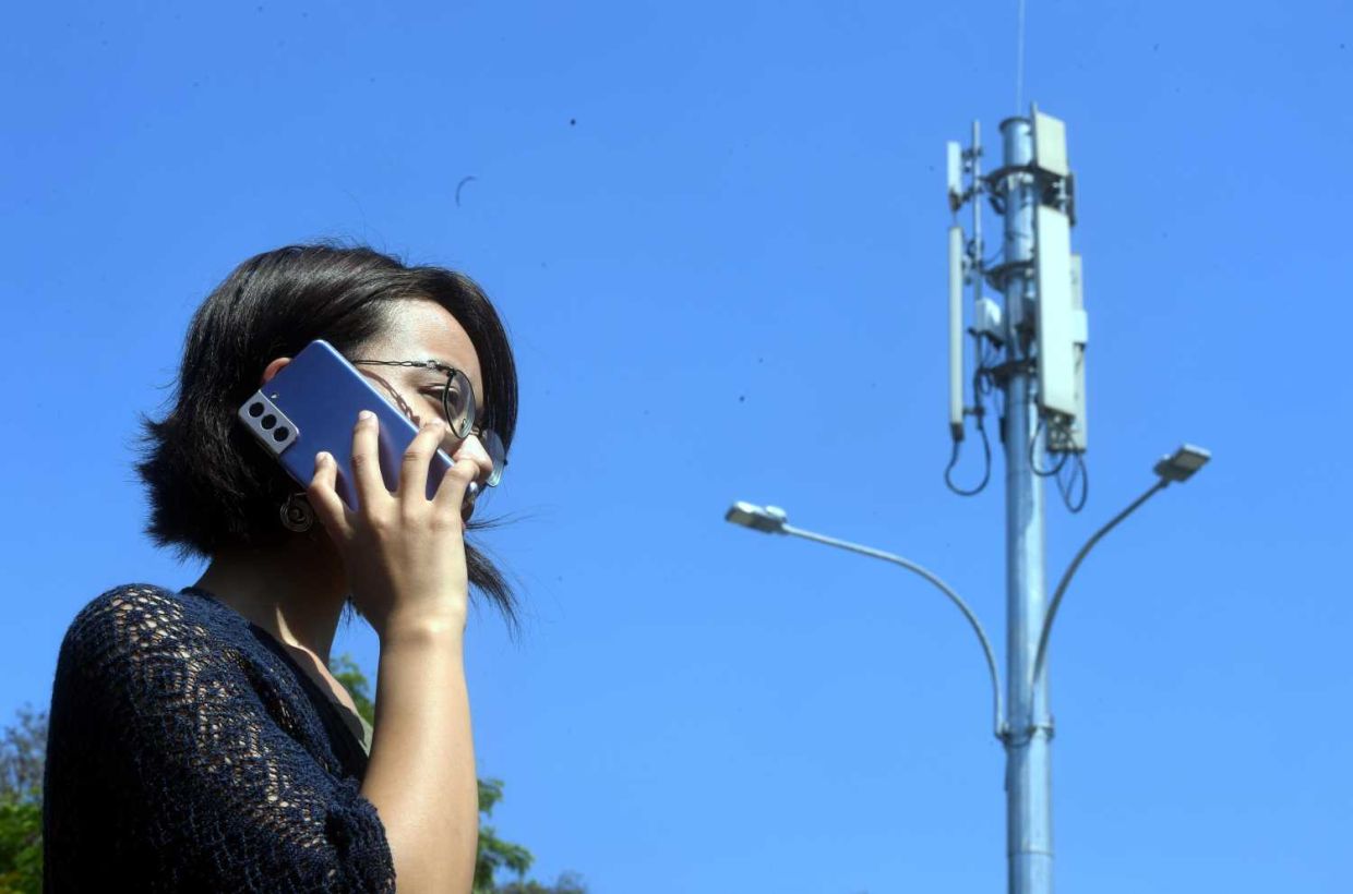 A women using her mobile phone near the Telco antenna in Kuala Lumpur(29/2/2024). —AZHAR MAHFOF/The Star