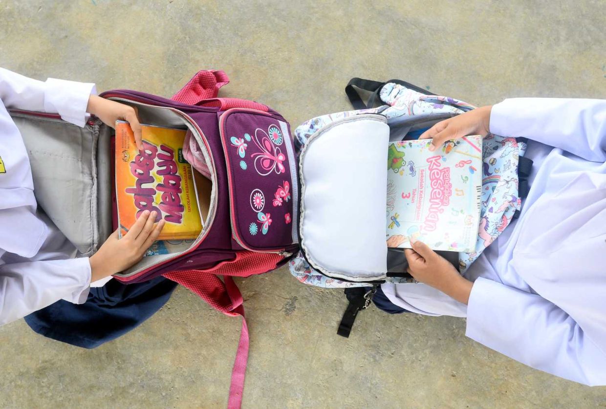 Primary school students arranging books into their bags . Story on reduce of books in students schools bags. (14/4/2022). —AZHAR MAHFOF/The Star