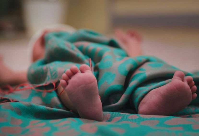 Newborn baby feet in bed close up. Happy Family concept. Beautiful conceptual image of Maternity. Useful as greeting card. Selective focus