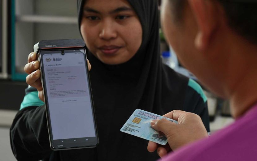 A staff at a petrol station helps Mohamad Zakwan to check his eligibility for Budi95 initiative. Some 16mil Malaysian aged 16 and above who hold a MyKad and valid driving licence will be eligible for the initiative begining Sept 30. (September 29, 2025) — ZHAFARAN NASIB/The Star.