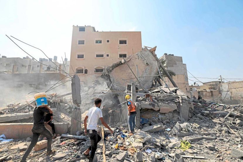 LEAD PIC: Bombarded: Palestinians surveing the rubble of a collapsed building following an Israeli strike yesterday in Khan Yunis in the southern Gaza Strip. -- AFP