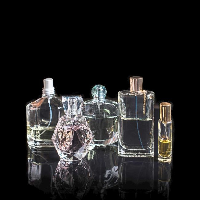 Different perfume bottles with reflections on black background with space for text. Perfumery, cosmetics, fragrance collection