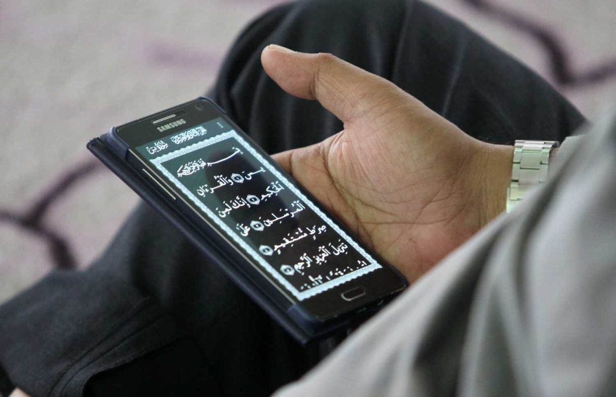 A man reads Al- Quran by using mobile apps , during the month of Ramadan in the Jamek Mosque in Kuala Lumpur.AZHAR MAHFOF/The Star