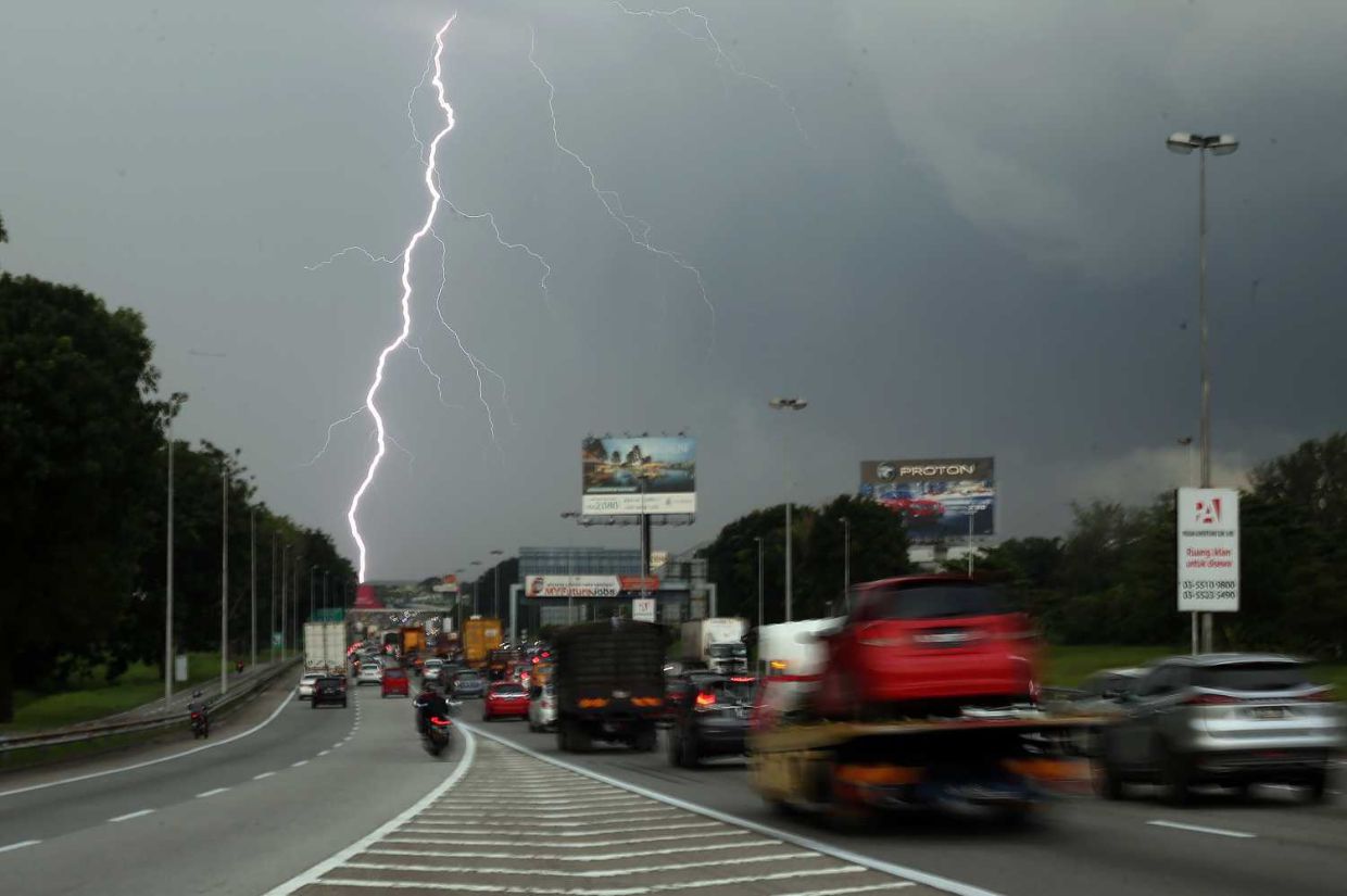 Lightning appears as dark cloud caryying heavy rain approaching the Kesas highway heading towards Kuala Lumpur on Monday. — IZZRAFIQ ALIAS/The Star
