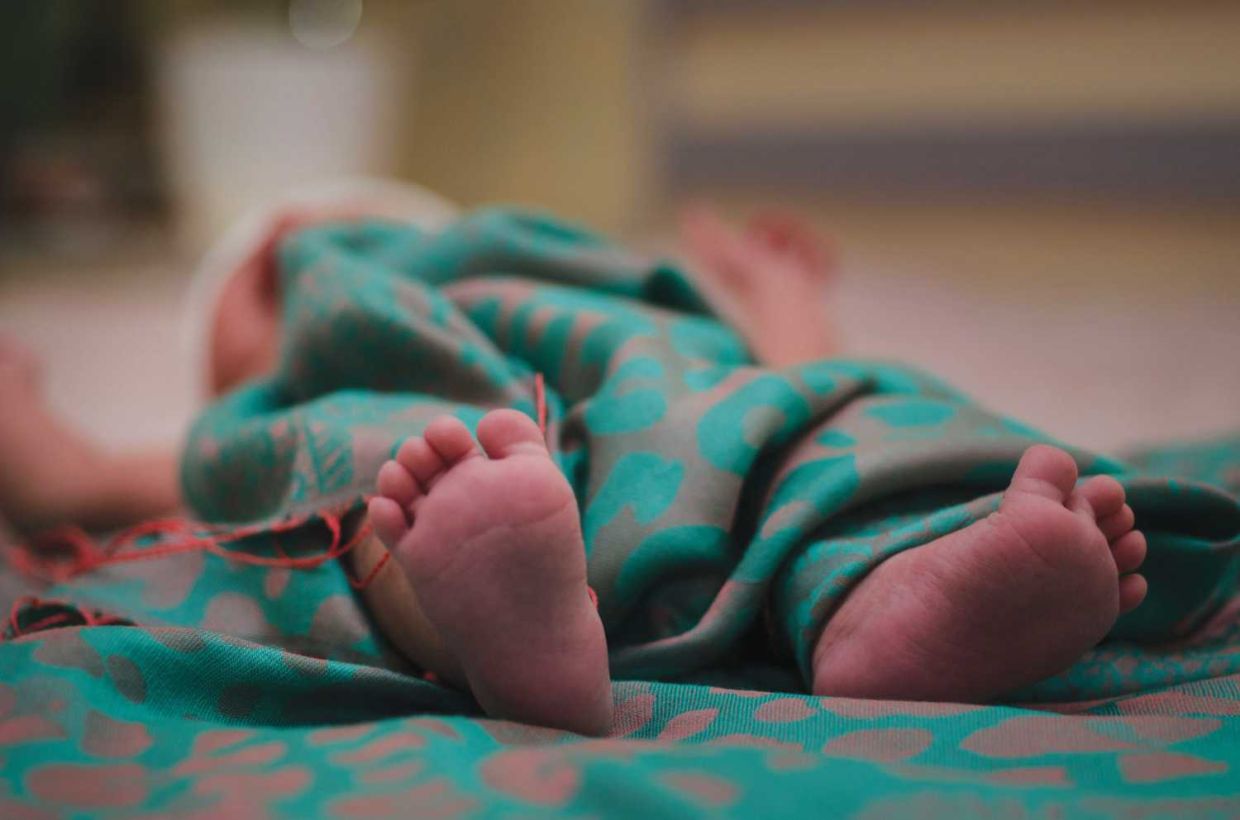 Newborn baby feet in bed close up. Happy Family concept. Beautiful conceptual image of Maternity. Useful as greeting card. Selective focus