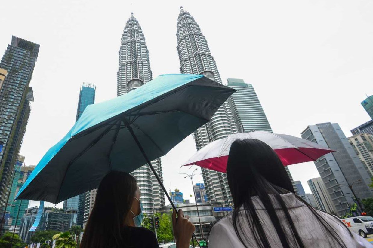 Womensuseumbrellas to protect themself from the scorching of the Sunin Kuala Lumpur city centre.(11/5/2022). —AZHAR MAHFOF/The Star
