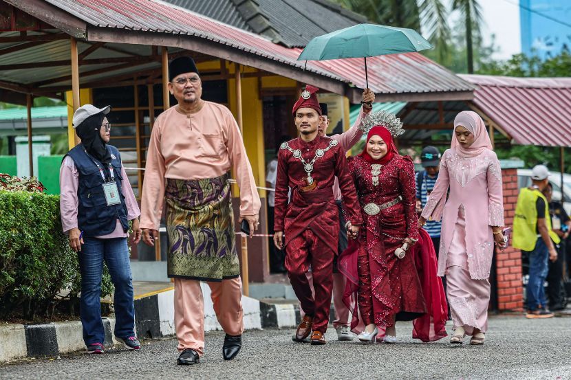 Pasangan pengantin baharu, Nurul Aida Mohd. Kamal dan Raja Akmal Hakim Raja Abdul Rahim, menunaikan tanggungjawab mengundi di Sekolah Kebangsaan (LKTP) Ayer Hitam pada Sabtu.