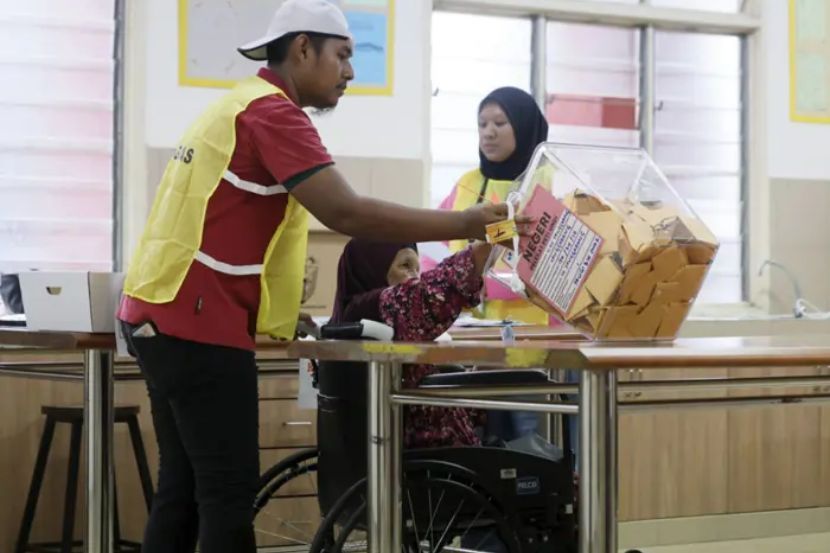 Petugas Suruhanjaya Pilihan Raya (SPR) membantu warga emas Siti Anipah Kasbolah, 78, mengundi ketika melaksanakan tanggungjawab mengundi bagi kerusi Dewan Undangan Negeri (DUN) N.24 Senggarang pada Pilihan Raya Negeri (PRN) Johor ke-16 di Pusat Menggundi Sekolah Kebangsaan Senggarang. -Foto Bernana