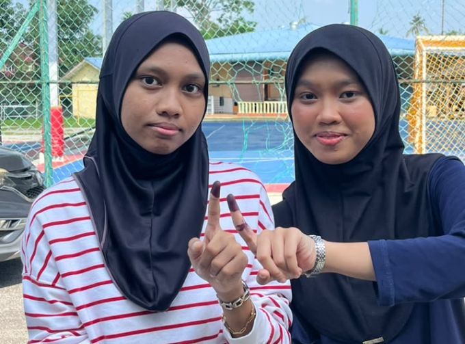 Dua beradik menunjukkan jari yang sudah dicalit. 