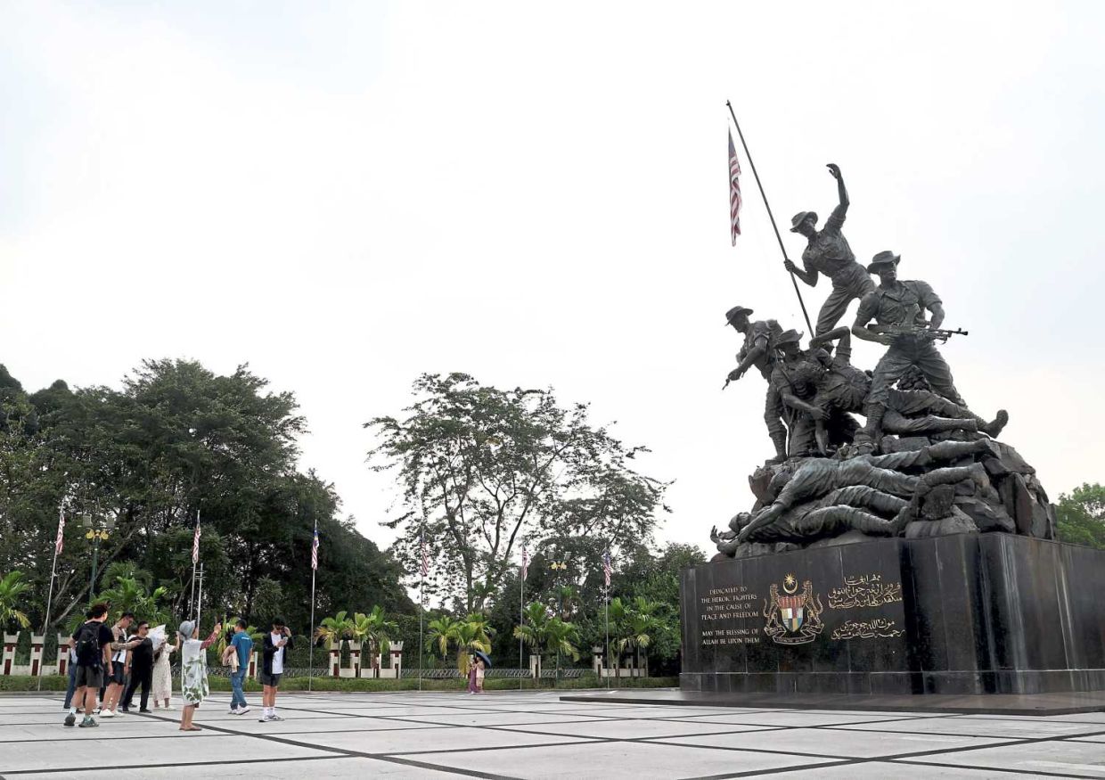 Despite Malaysia's hot weather, many tourists continue to visit Tugu Negara, shielding themselves from the sun with hats and umbrellas to enjoy the historical site. (FEB 14 2025) — ART CHEN/The Star