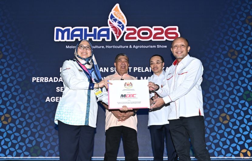 Aina Azza Zaid, menyampaikan surat pelantikan MDEC sebagai Pengesah Teknologi Digital Strategik Nasional dan Agensi Pelaksana Program Digital AgTech KPKM kepada Ir. Wan Murdani Wan Mohamad, sambil disaksikan Datuk SeriMohamad Sabu (belakang kiri) dan Datuk Seri Norazman Ayob (belakang kanan) di MAHA 2026.