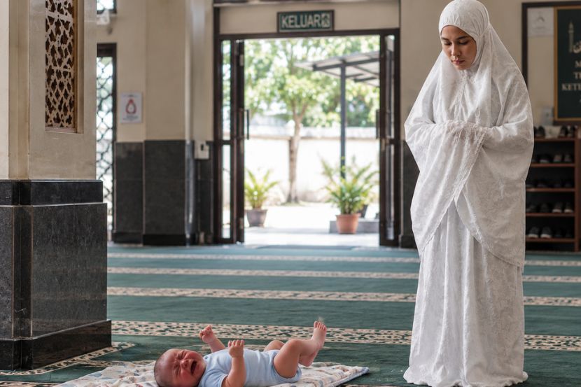 Meletakkan anak dihadapan ketika solat memudahkan ibu memantau keselamatan anak. -Gambar hiasan AI