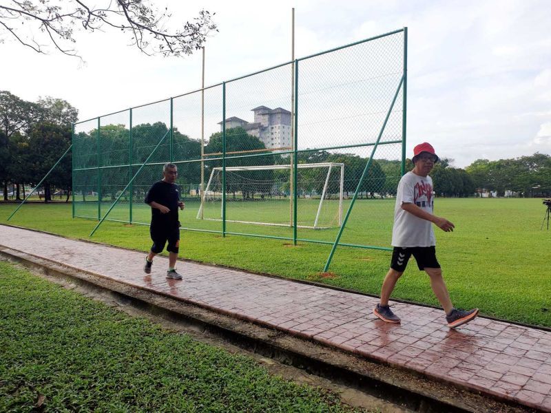 Residents doing brisk walks along the walk path next to the chain-link fence behind the goal post at the USJ 11 park off Jalan USJ11/5 in USJ 11, Subang Jaya.