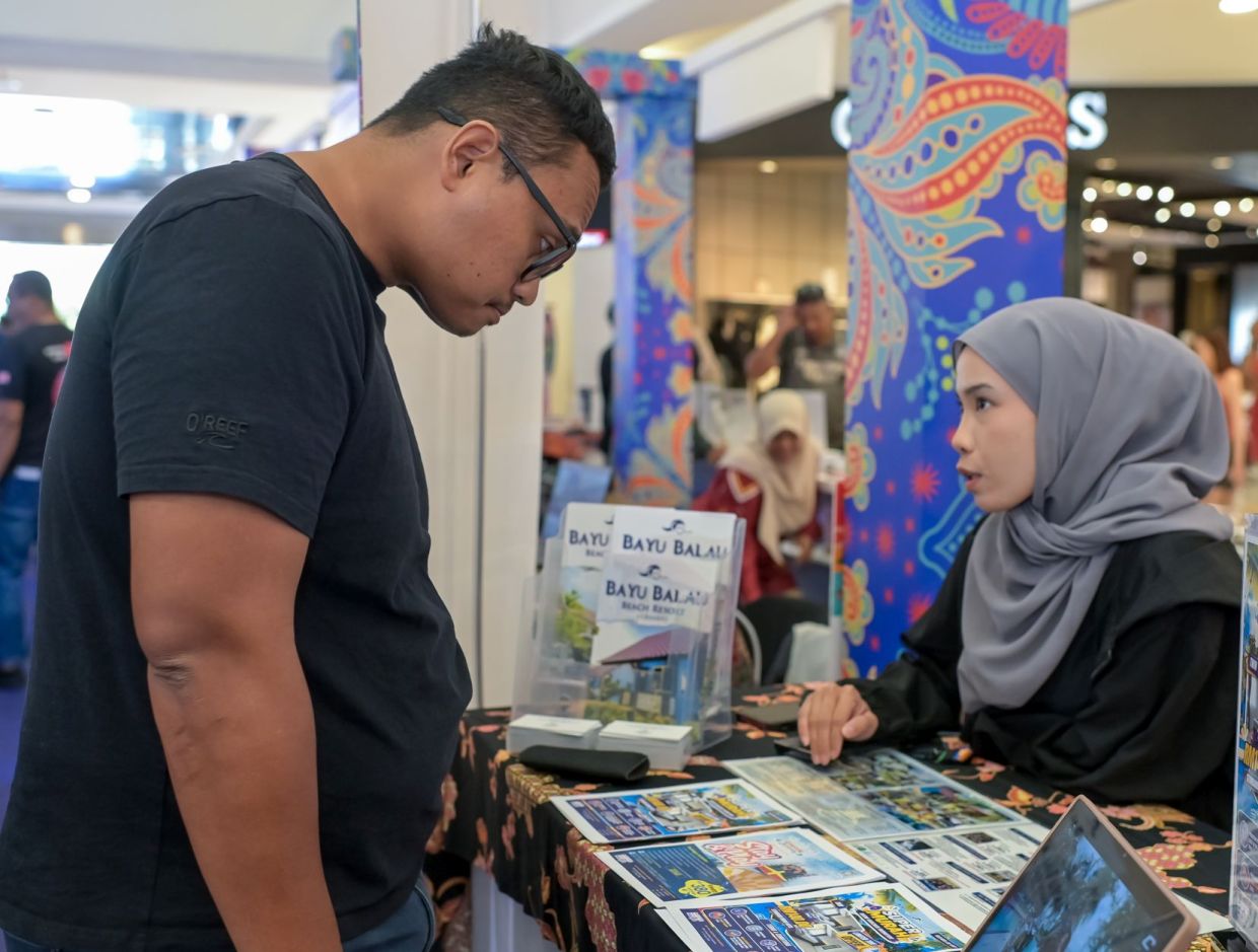 Pengunjung meneliti brosur dan mendapatkan penerangan mengenai pakej percutian di salah sebuah reruai pameran Star Karnival Cuti-Cuti Malaysia. 