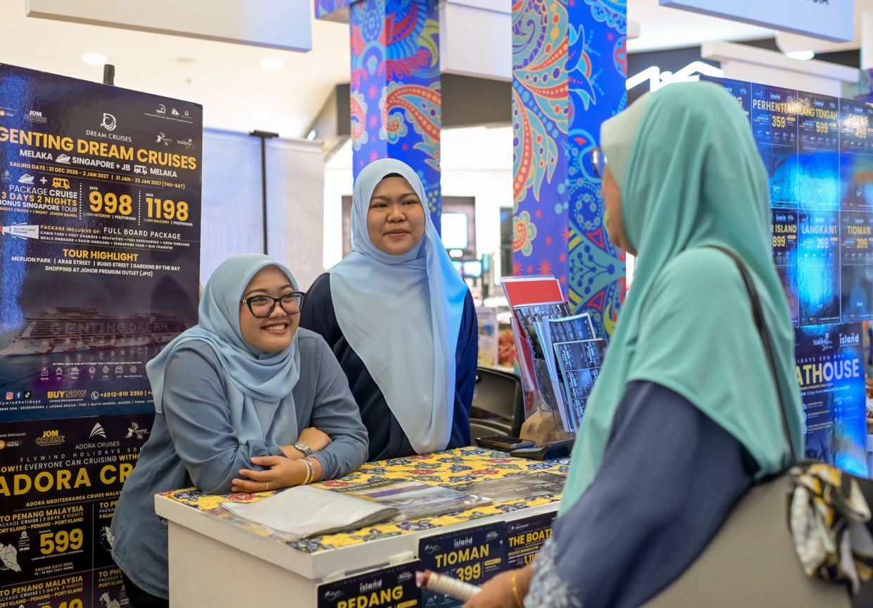 Wakil pempamer berkongsi maklumat mengenai tawaran penginapan dan pakej percutian kepada pengunjung yang singgah di reruai mereka.